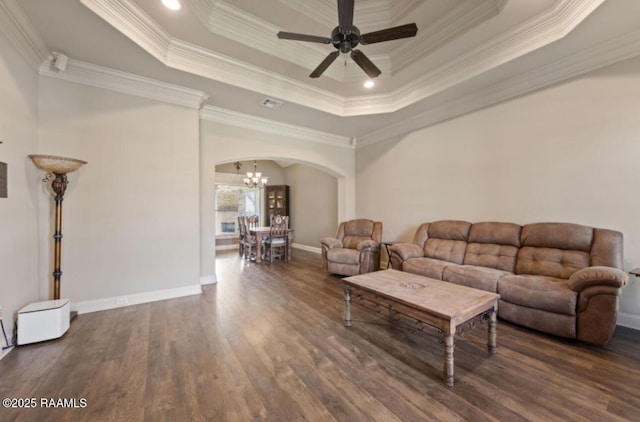 living room with a raised ceiling, crown molding, dark hardwood / wood-style floors, and ceiling fan with notable chandelier