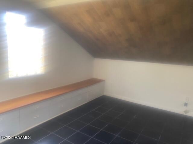 additional living space with lofted ceiling and dark tile patterned flooring