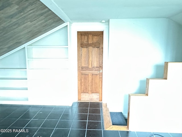 additional living space with dark tile patterned floors and vaulted ceiling