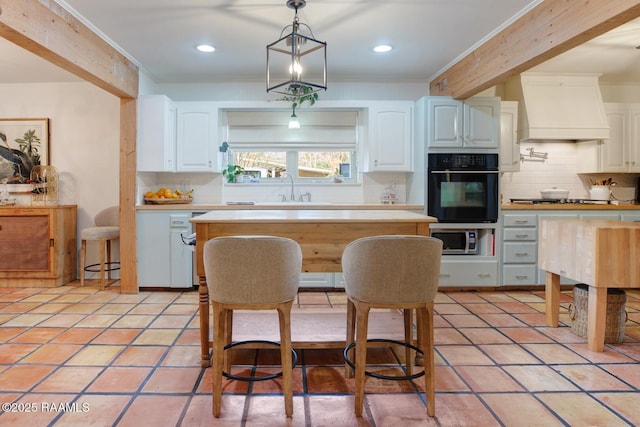 kitchen featuring sink, custom exhaust hood, hanging light fixtures, stainless steel appliances, and white cabinets