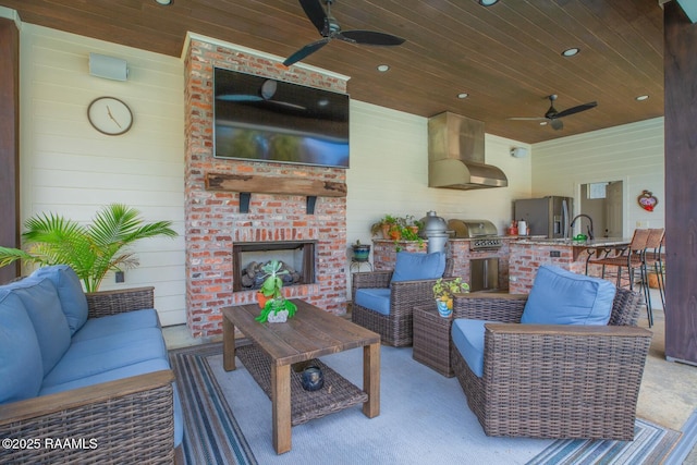 view of patio / terrace with a grill, an outdoor living space with a fireplace, ceiling fan, and exterior kitchen