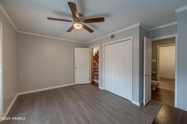 unfurnished bedroom featuring ornamental molding, ceiling fan, dark wood-type flooring, a textured ceiling, and a closet