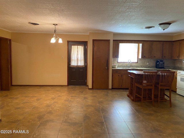 kitchen featuring sink, an inviting chandelier, crown molding, hanging light fixtures, and decorative backsplash