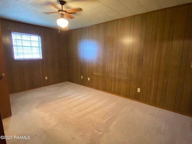 unfurnished room with carpet floors, ceiling fan, and wood walls