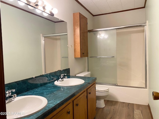 bathroom featuring wood finished floors, crown molding, and a sink