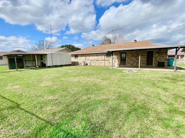 back of property with an outbuilding, a patio, a yard, a fire pit, and brick siding