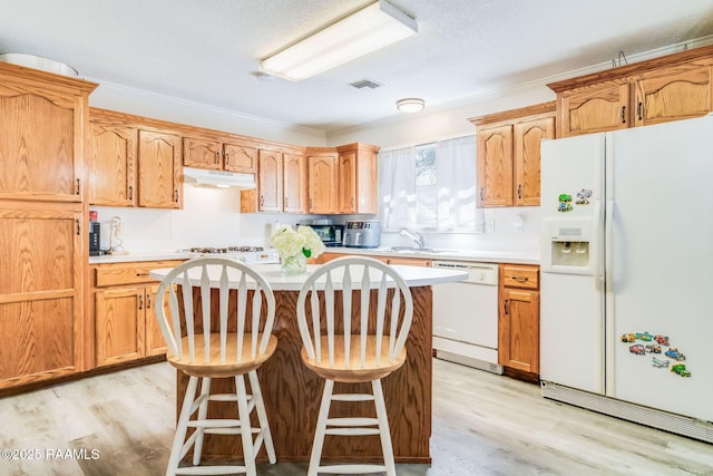 kitchen featuring white appliances, a center island, light hardwood / wood-style floors, and a breakfast bar area