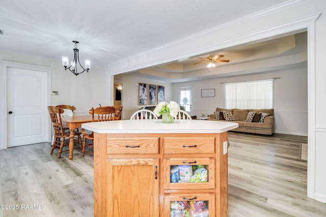 kitchen with pendant lighting, crown molding, light hardwood / wood-style floors, a raised ceiling, and light brown cabinets