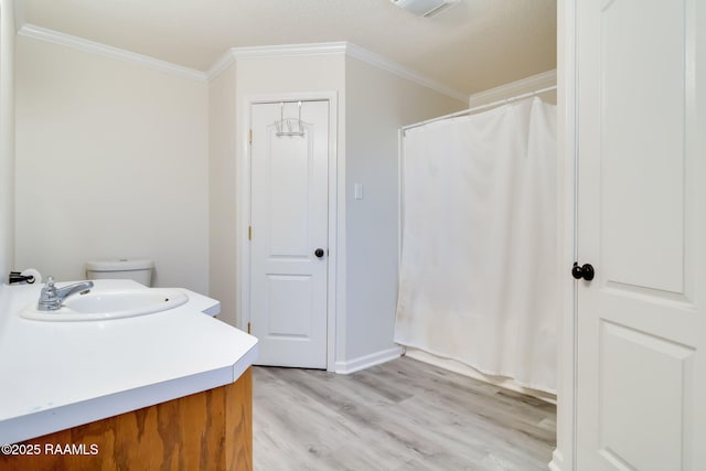 bathroom with hardwood / wood-style flooring, crown molding, vanity, and toilet