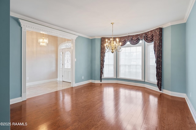 spare room featuring an inviting chandelier, crown molding, and light wood-type flooring