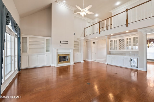 unfurnished living room with a high ceiling, crown molding, hardwood / wood-style floors, and a fireplace