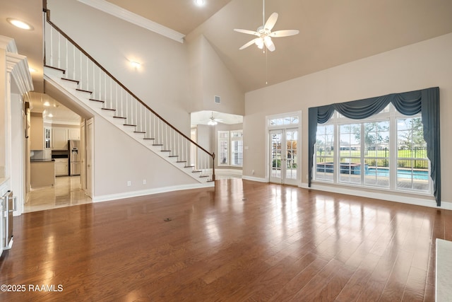 unfurnished living room featuring hardwood / wood-style flooring, french doors, ceiling fan, and a high ceiling