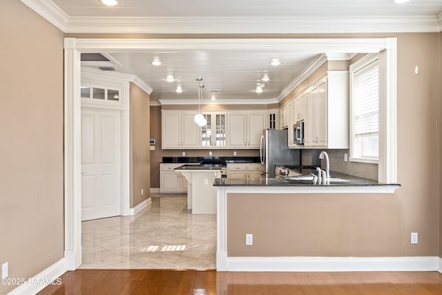 kitchen with crown molding, stainless steel appliances, kitchen peninsula, and sink