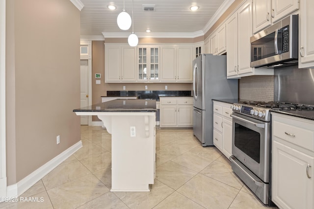 kitchen with a kitchen island, appliances with stainless steel finishes, white cabinetry, a breakfast bar area, and ornamental molding