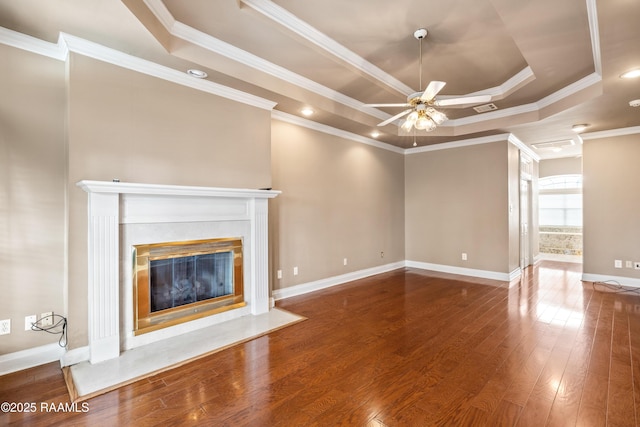 unfurnished living room featuring ceiling fan, a high end fireplace, a tray ceiling, and hardwood / wood-style floors