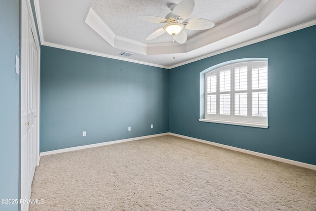 carpeted spare room featuring a tray ceiling, ornamental molding, ceiling fan, and a textured ceiling