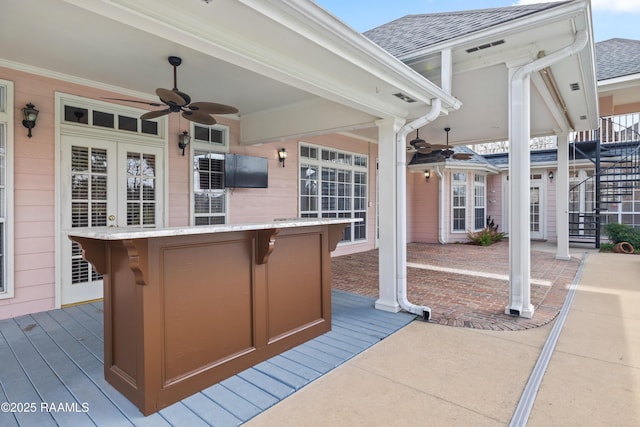 view of patio featuring a bar, ceiling fan, and a deck