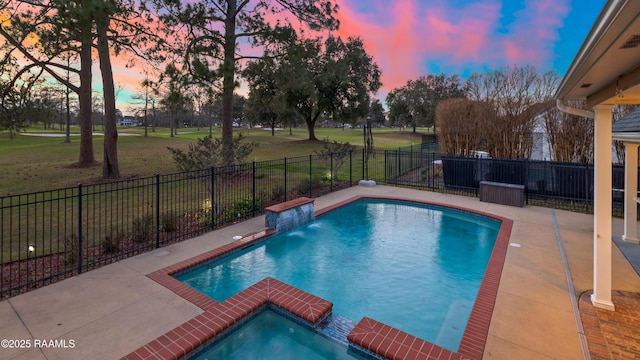 pool at dusk featuring a patio, pool water feature, an in ground hot tub, and a lawn