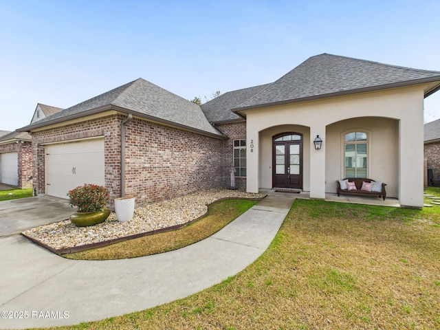 view of front of home with a garage, a shingled roof, brick siding, french doors, and a front yard