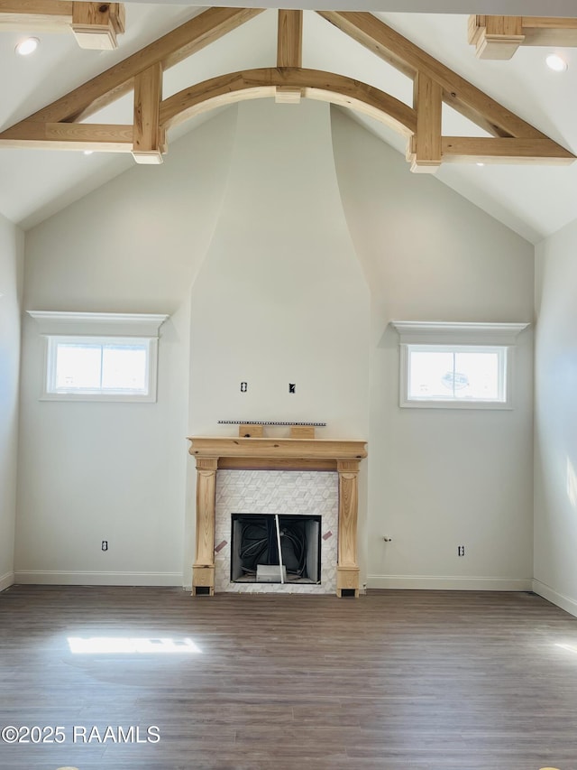 unfurnished living room featuring beam ceiling, a fireplace, hardwood / wood-style flooring, and plenty of natural light