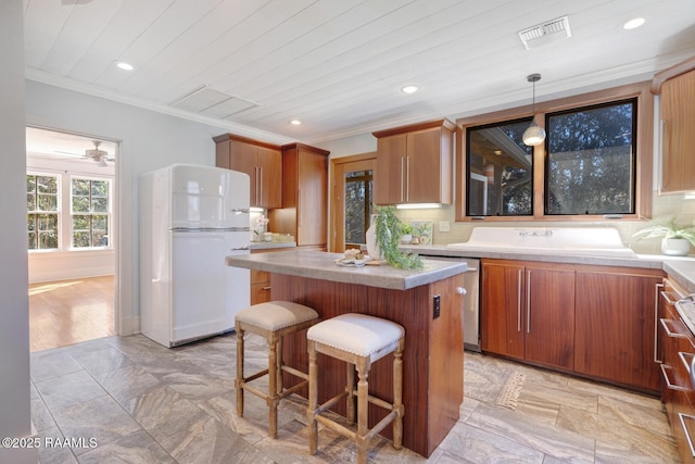 kitchen featuring visible vents, light countertops, freestanding refrigerator, and decorative light fixtures