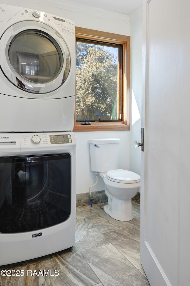 washroom featuring ornamental molding and stacked washer / dryer