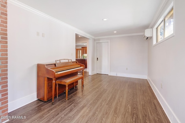 sitting room with an AC wall unit, crown molding, baseboards, and wood finished floors