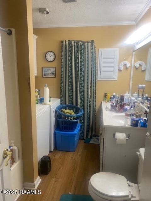 bathroom featuring crown molding, wood-type flooring, washer and dryer, a textured ceiling, and vanity