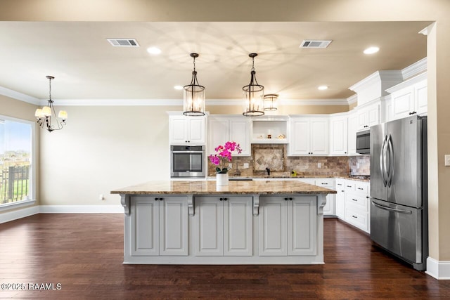 kitchen with light stone counters, stainless steel appliances, white cabinets, and a kitchen island