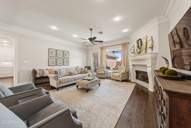 living room with ornamental molding, dark wood-type flooring, and ceiling fan