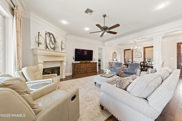 living room with ceiling fan with notable chandelier, dark wood-type flooring, and ornamental molding