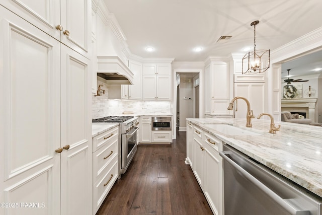 kitchen with premium range hood, sink, appliances with stainless steel finishes, pendant lighting, and white cabinets