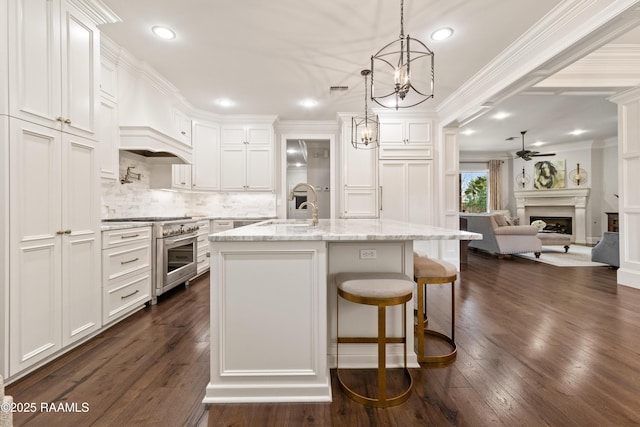 kitchen with pendant lighting, sink, a kitchen island with sink, and light stone counters