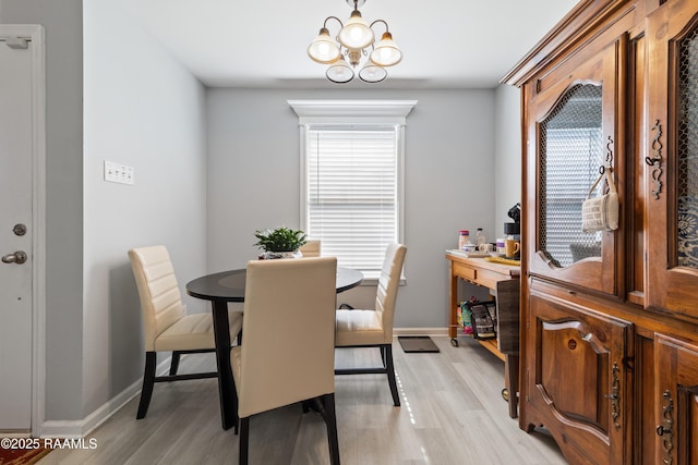 dining space with light wood-type flooring and an inviting chandelier