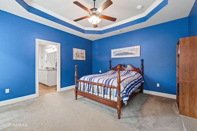 carpeted bedroom with crown molding, connected bathroom, ceiling fan, and a tray ceiling