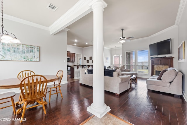 living room with ornamental molding, dark wood-type flooring, decorative columns, and ceiling fan