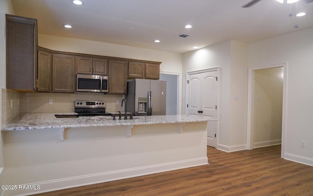 kitchen featuring appliances with stainless steel finishes, sink, a breakfast bar area, and light stone counters