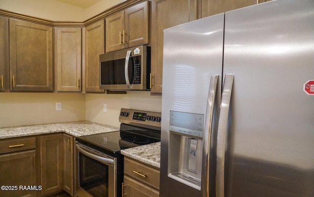 kitchen with decorative backsplash, light stone countertops, and appliances with stainless steel finishes