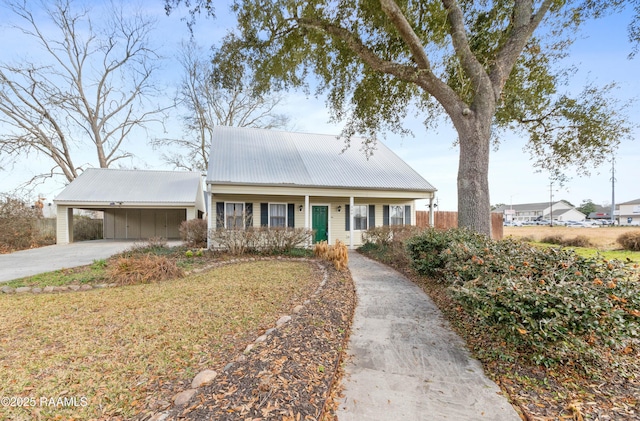 view of front of house featuring a porch, driveway, metal roof, and a carport