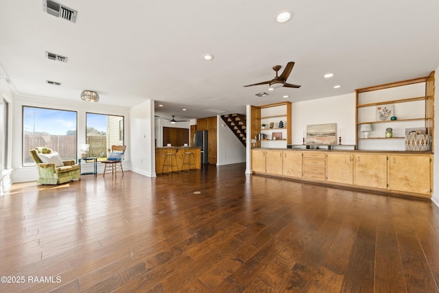 unfurnished living room featuring dark wood-style floors, visible vents, and a ceiling fan