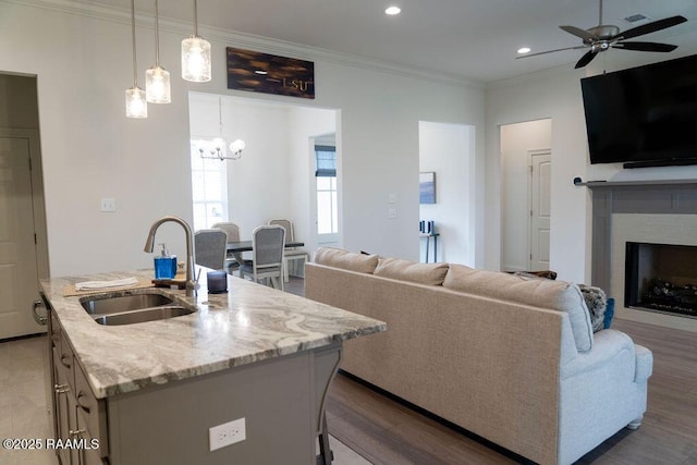 living room featuring sink, hardwood / wood-style flooring, ornamental molding, and ceiling fan