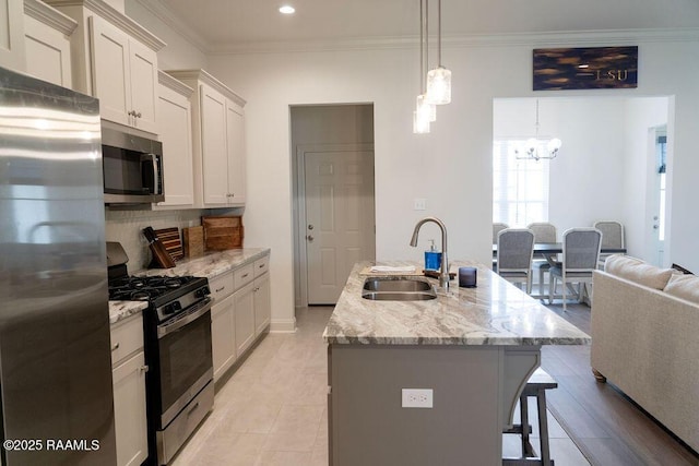 kitchen with sink, a center island with sink, hanging light fixtures, and appliances with stainless steel finishes