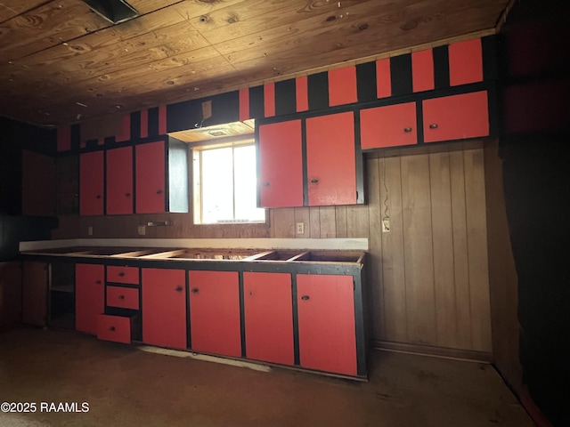 kitchen featuring wood ceiling, red cabinets, and wooden walls