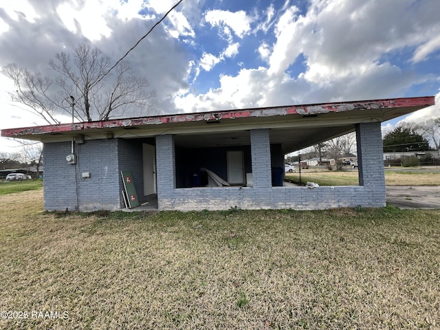 back of house with a carport, a lawn, and brick siding