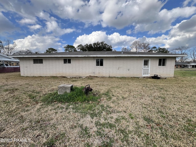 back of property with brick siding and a lawn