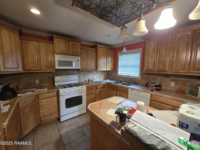 kitchen with pendant lighting, white appliances, sink, and tasteful backsplash