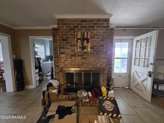 living room with crown molding, washer / dryer, a healthy amount of sunlight, and a brick fireplace