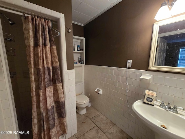 bathroom with tile patterned floors, toilet, sink, tile walls, and a shower with shower curtain