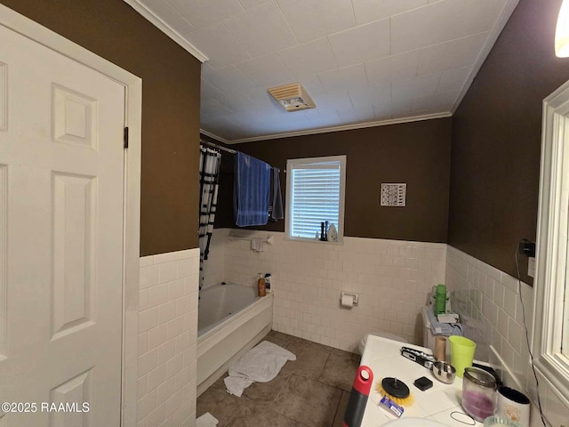 bathroom with ornamental molding, tile patterned floors, tile walls, and a washtub