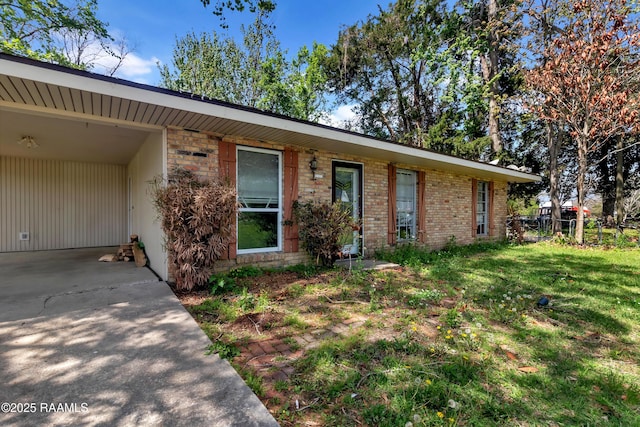ranch-style house with an attached carport, a front yard, brick siding, and driveway